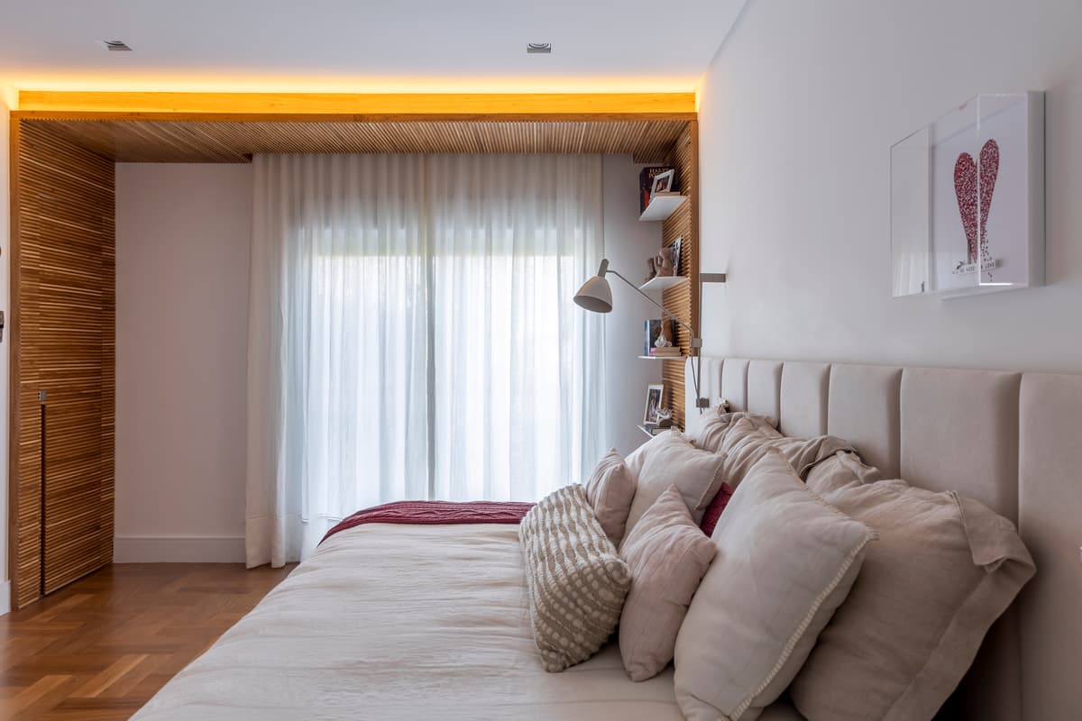 Quarto de casal com cabeceira estofada e iluminação embutida no forro