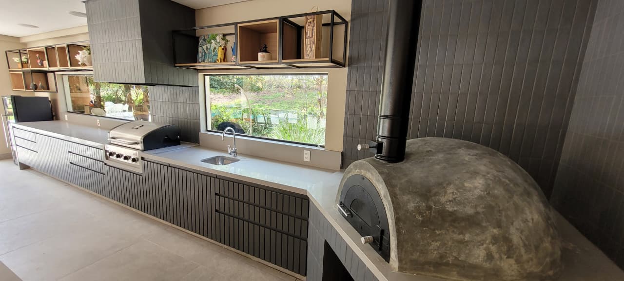 Área gourmet com bancada, churrasqueira e forno a lenha