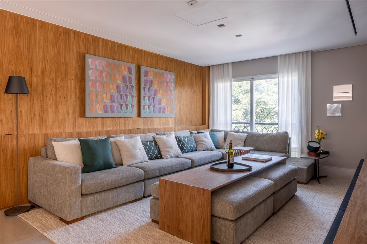 Sala de estar com painel de madeira, sofá em L e mesa de centro em madeira